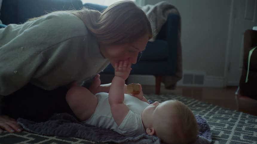 Mother playing with her baby who is lying on the carpet