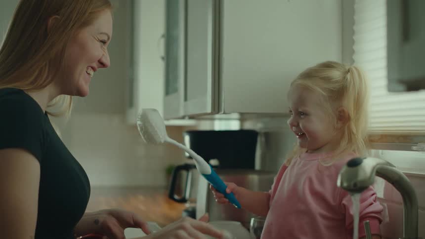 Mother and daughter have fun washing the dishes