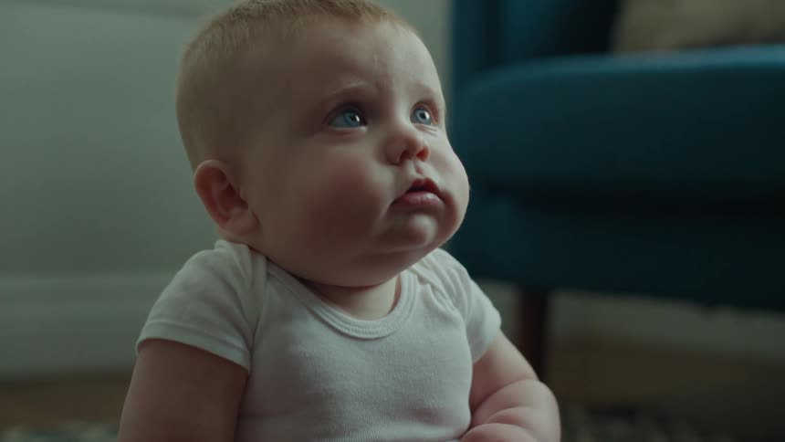 Portrait of a male baby sitting on the living room floor with various facial expressions