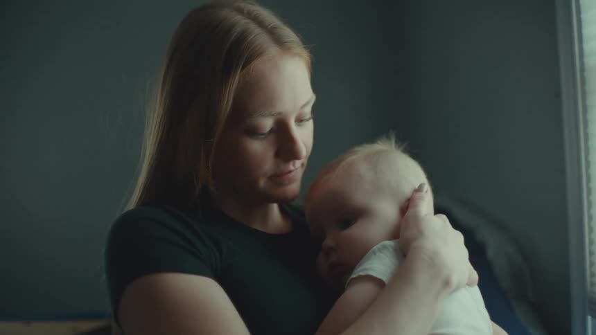 Mother holding her child sways slightly and smiles