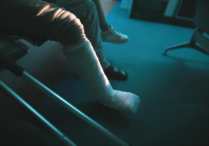 Person sitting on hospital chairs with their leg bandaged