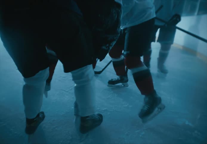Injured hockey player being helped up off the ice rink by teammates