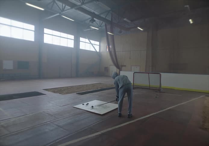 A man is shooting hockey pucks into the net