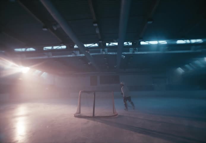 A hockey player skating on an empty hockey court