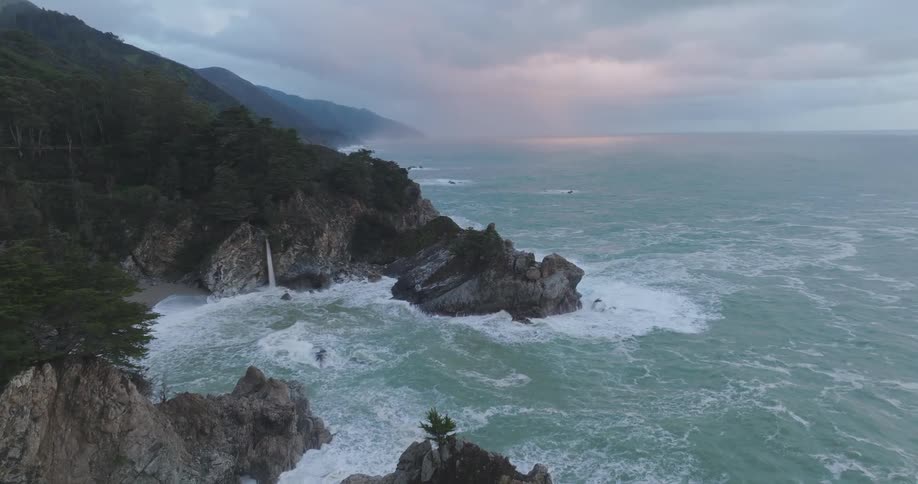 Waves crash against the island on a cloudy day