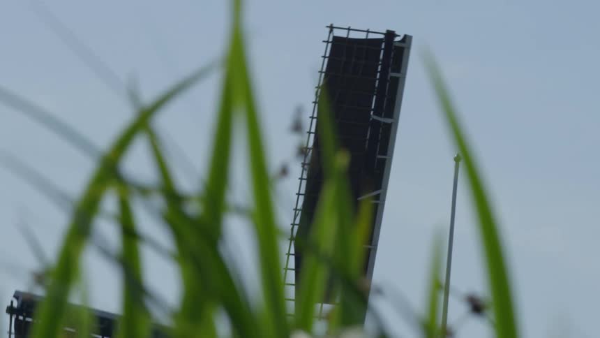 A windmill spins past blades of grass