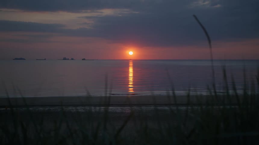 The sun low over the ocean near a beach