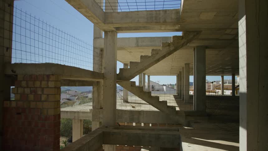 An unfinished building with a concrete staircase and a view of the sky and buildings