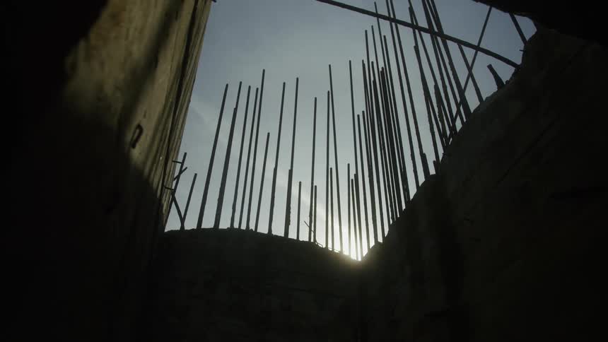 Rebar sticks up out of the ground near a structure