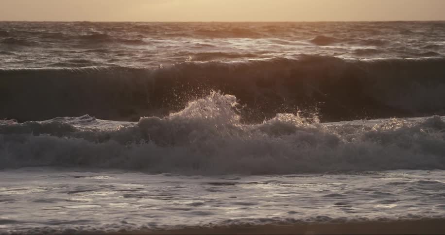 Man diving a wave in the middle of the sea with the sunrise on the horizon