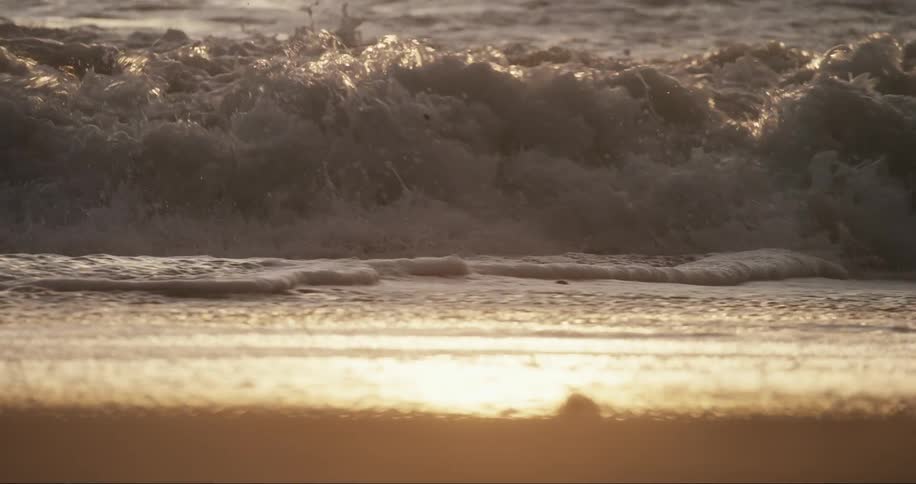 Sunlight reflected in the sea waves hitting the beach