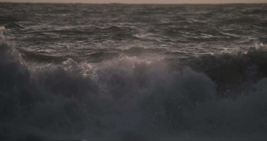 Choppy waves crash into the sea during sunset