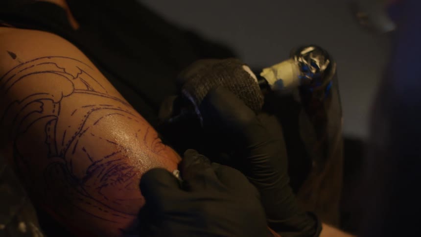 A man tattooing someone elses skin