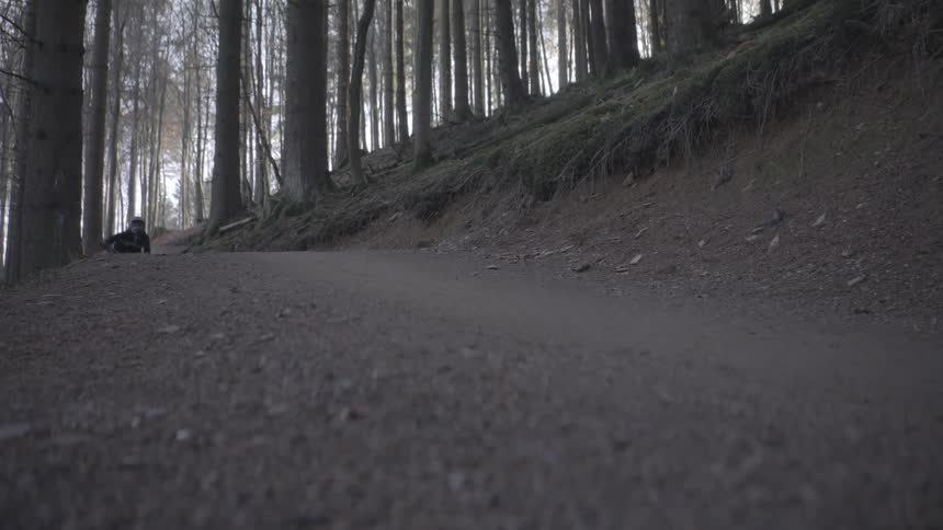A teenager riding a bike on a trail through the woods leaps into the air