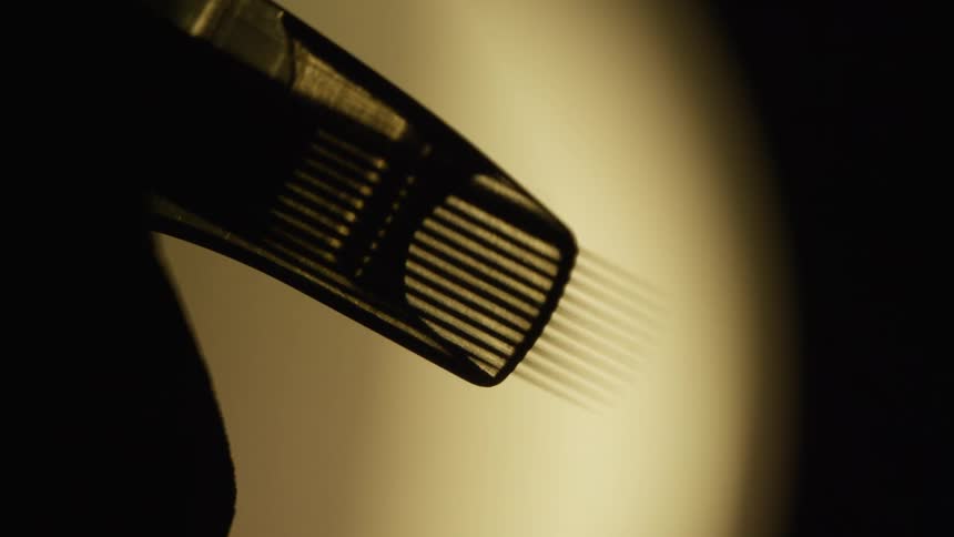 A silhouette of a small machine with several needles at the end going back and forth quickly