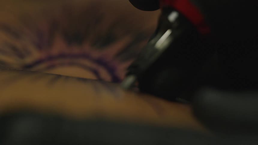 A tattoo artist carefully places a tattoo on the skin of the recipient