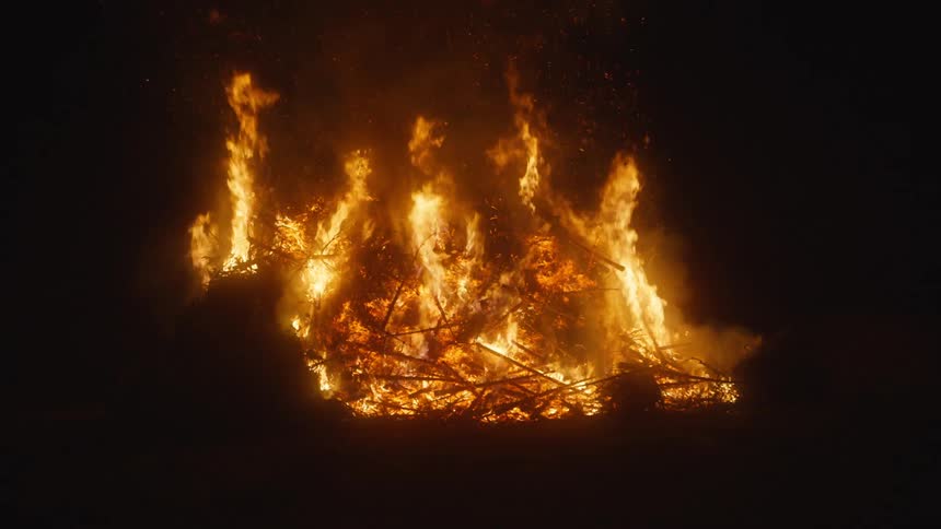 Flames of a large outdoor bonfire at night