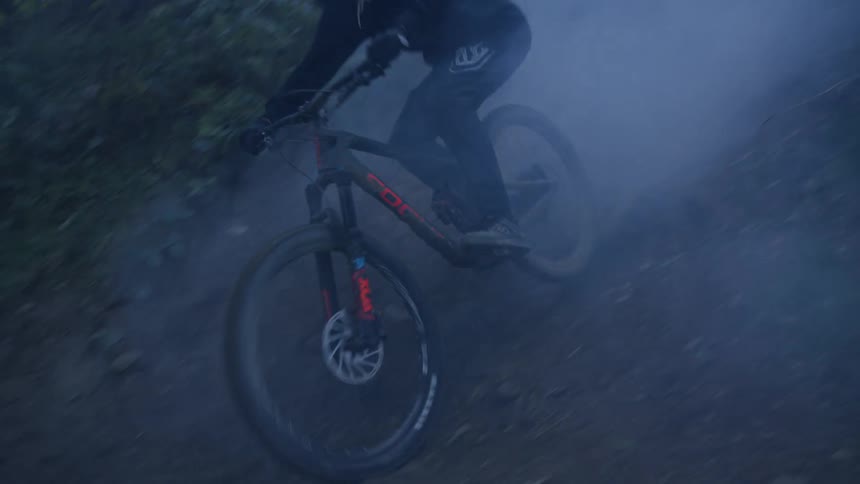 A person riding a mountain bike through the mist in the forest