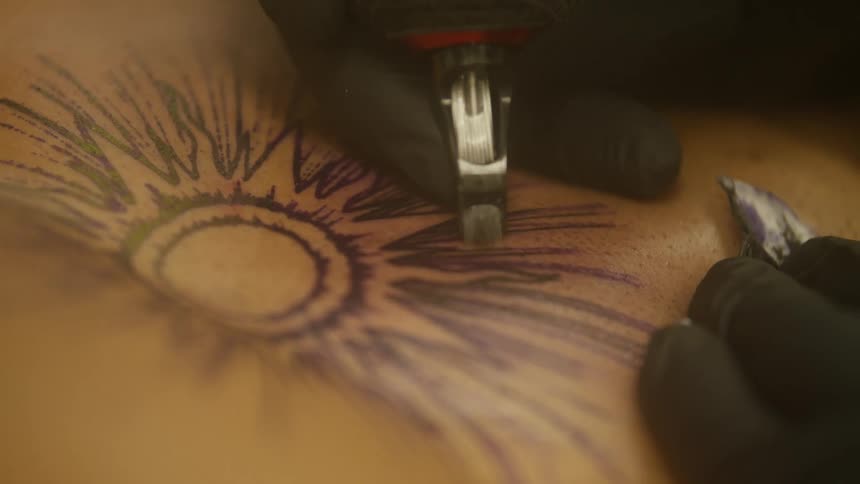 A person tattoos a sun on another person