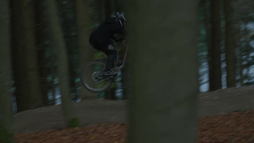 Biker cycles on winding road in the woods