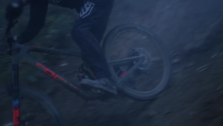 Person on a mountain bike descending a small hill in the middle of the forest