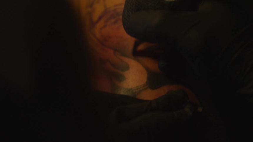 Closeup on the hands of a tattoo artist performing an artistic tattoo on a persons skin
