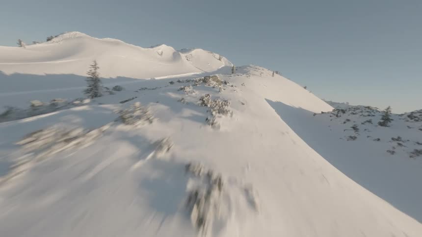 The camera soars up a snowcovered slope of a tall mountain