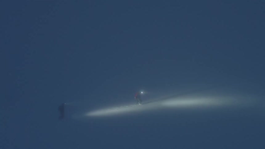 People climb a mountain during a blizzard at night