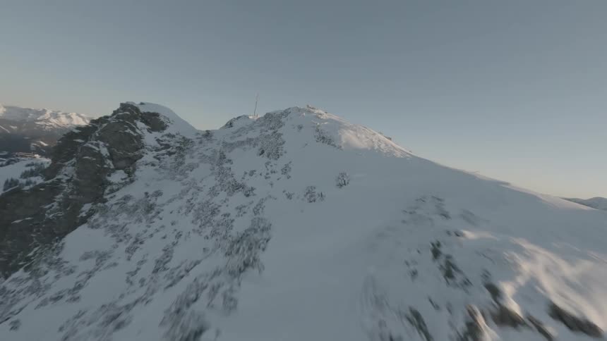 Moving over a snow covered mountain ridge under a clear sky