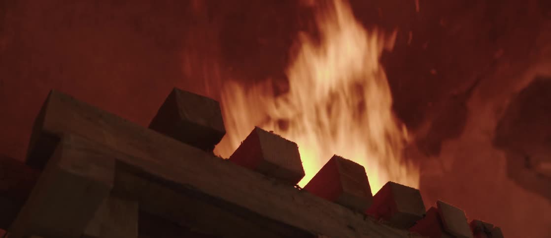 A bonfire with high flames on top of a wooden pallet