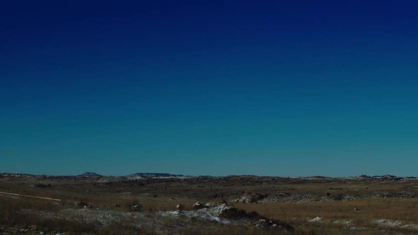 Flat landscape with rocks and vegetation and a cloudless blue sky day