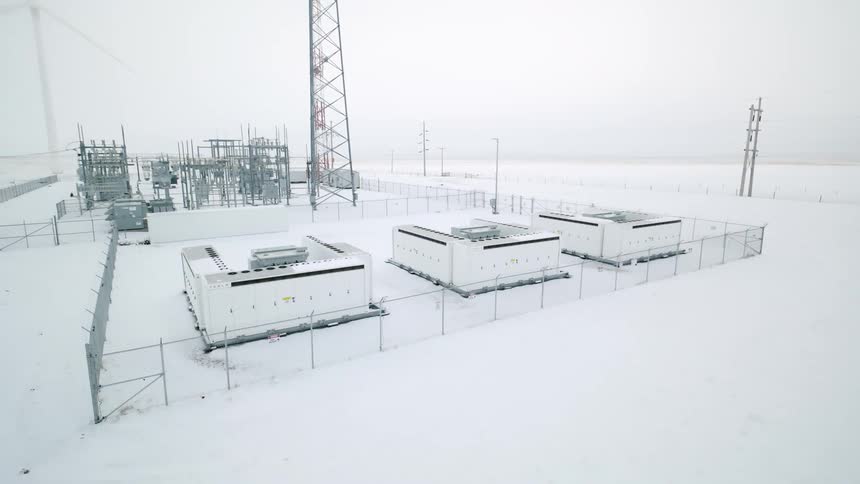 Power transmission towers and energy storage amid a field covered in snow in the morning
