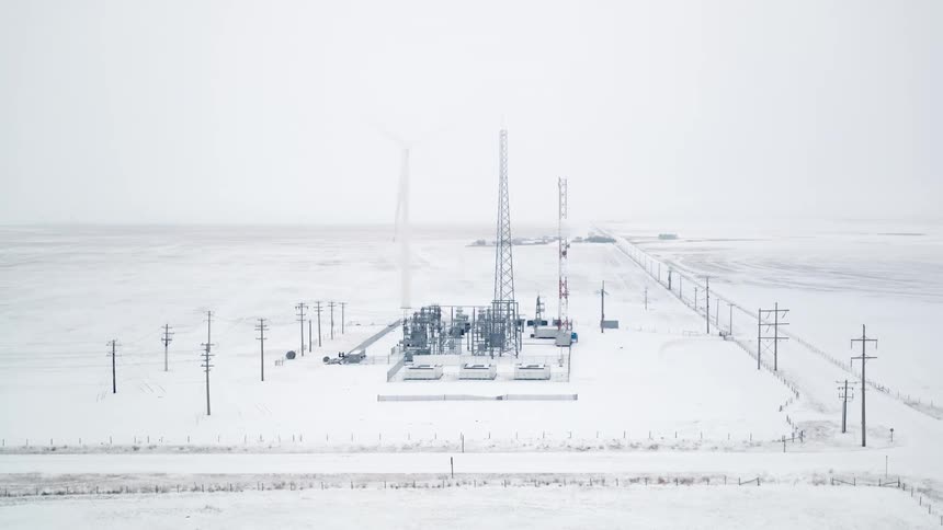 An aerial view of an electrical substation and communication towers on a snowy landscape