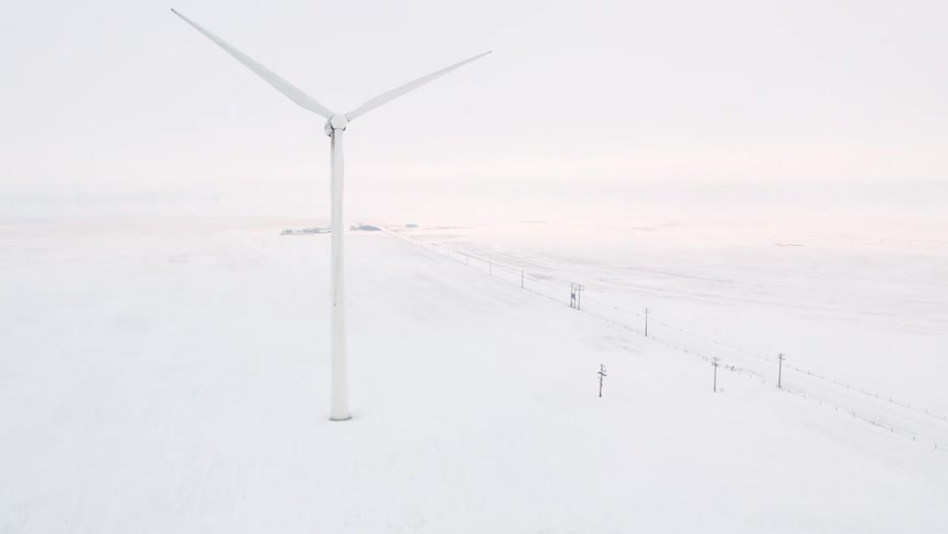 Electric power station and wind turbine on a snowcovered prairie on a foggy morning