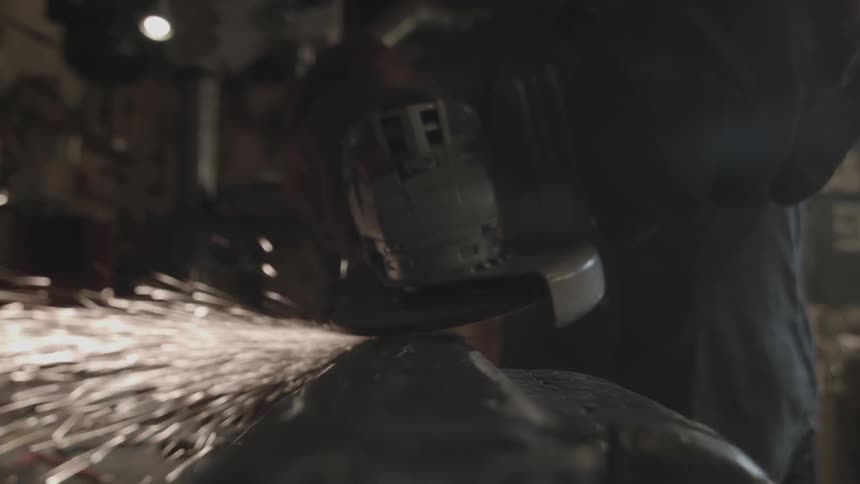 A person using a power tool on a steel plate in a workshop