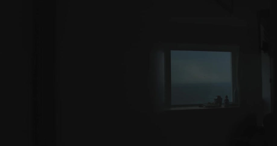Door opening overlooking a window with seascape in a dark morning sky
