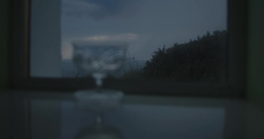 A glass cup sits in front of a window