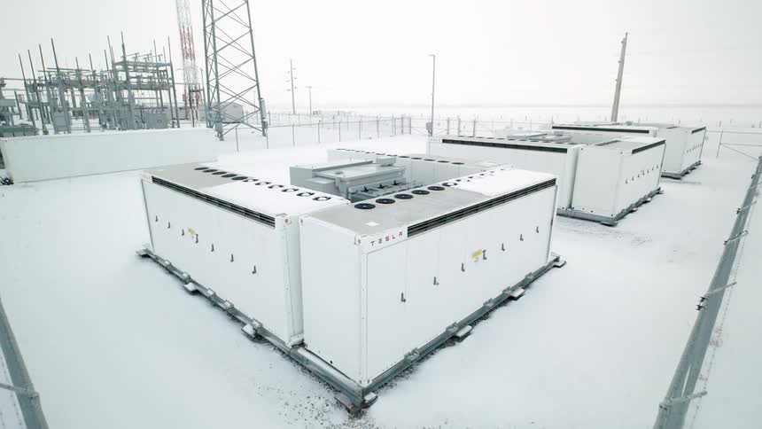 Flying over battery storage cabinets in an open space covered by snow