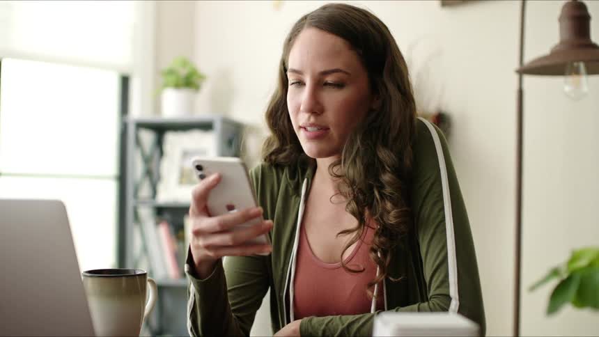 Young man and woman taking out their cell phone while sitting and smiling