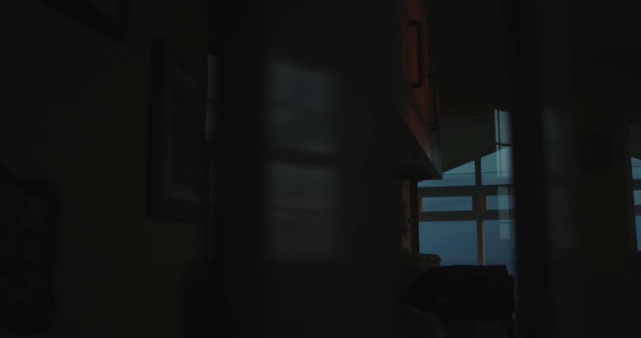 Interior of a dark house with a view of the window and a dark sky at dawn
