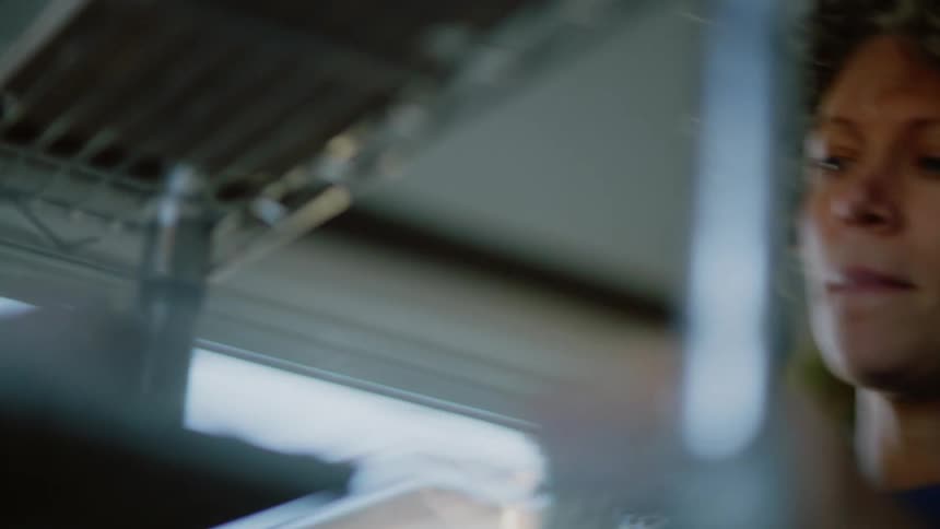 Closeup of a womans face placing objects on a shelf