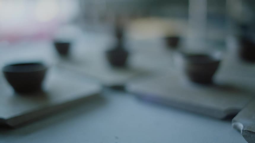 Closeup of a persons hand nailing pottery with a small glass