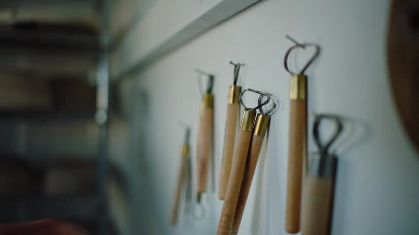 A person picking up a tool hanging on the wall