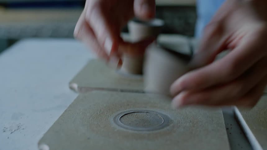 Womans hands removing small porcelain vases from a concrete surface