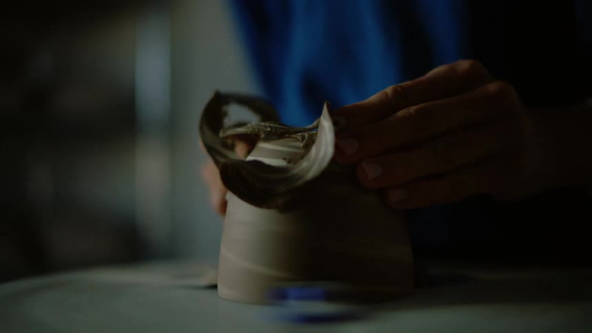 The hands of a person who is sculpting a clay object
