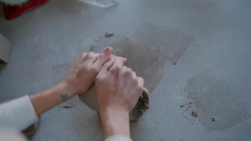 Closeup of a womans hands kneading clay on the table