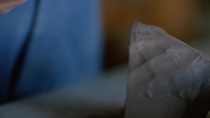 A person using a thread to cut a piece of clay in half