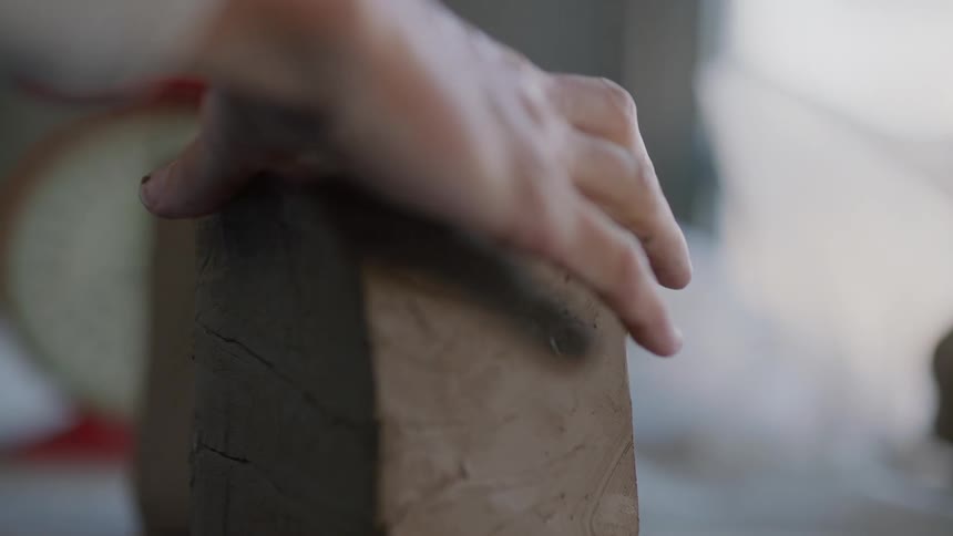 A womans hands cutting clay dough with a thread and then shaping it
