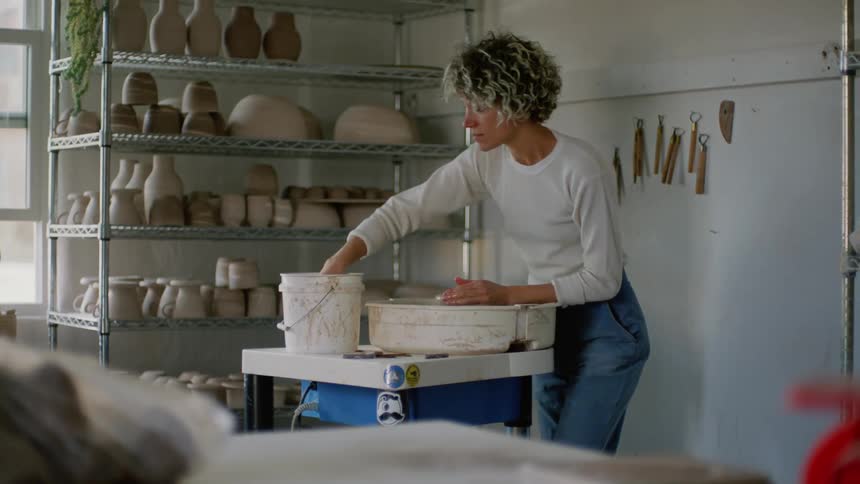 A white woman shapes a lump of clay