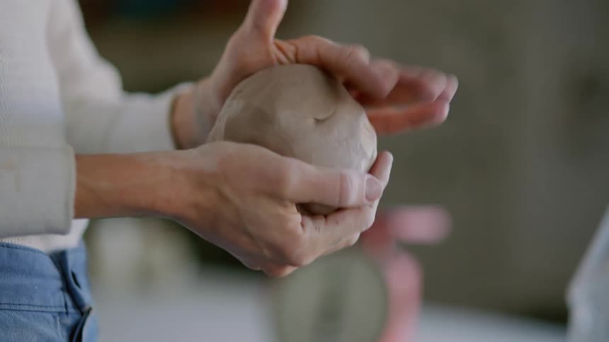 Woman hitting a ball of clay with her hands